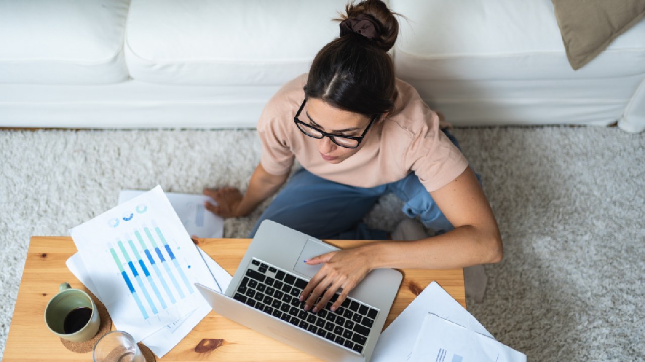 Small business owner reviewing financial reports and working on a laptop—exploring ways to improve cash flow in a small business.